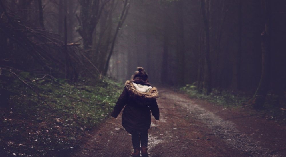 girl walking away down forest path, alone