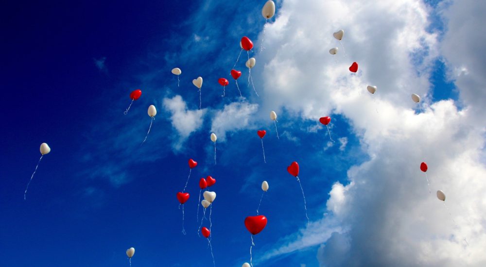 heart balloons floating in a blue sky