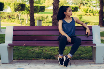woman enjoying nature-based relaxation sitting on a park bench