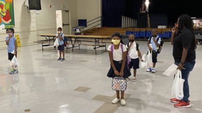 masked students in socially distanced lines go back to school during the COVID-19 pandemic