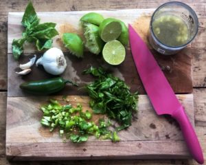 cutting board with herbs, garlic, and lime to make a dressing