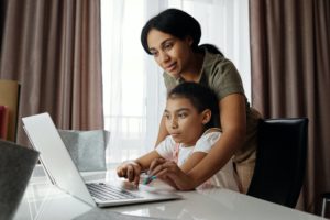 mom helps daughter on computer with at-home STEM learning
