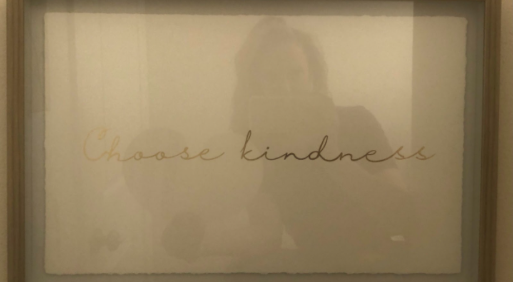 woman's reflection in a framed print reading choose kindness