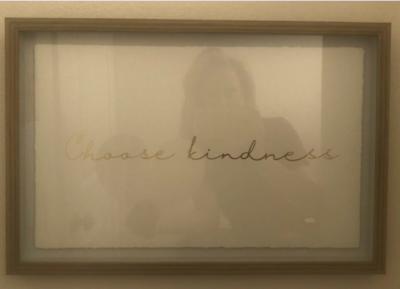 woman's reflection in a framed print reading choose kindness