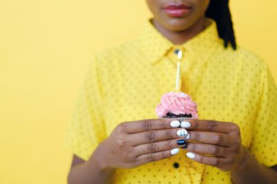 close-up on woman's hands holding a cupcake with birthday candle