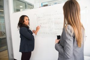 2 women drafting a communications plan on a whiteboard