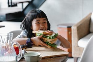 little girl smiling with a big sandwich
