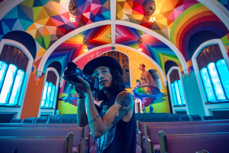 Colorful interior building, person with hat and tattoos taking photos