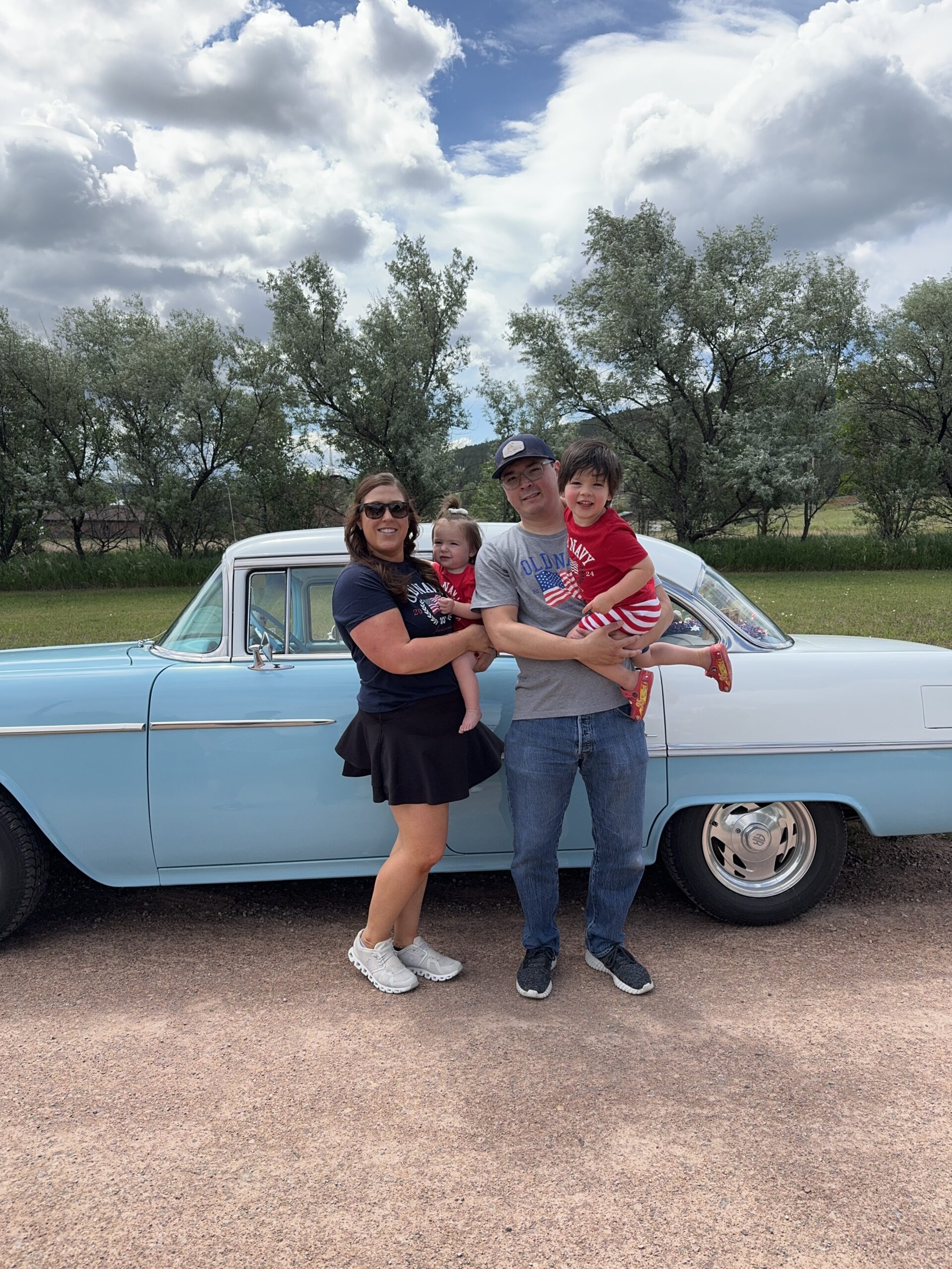 A photo of Kaitlin and her family by a blue car.