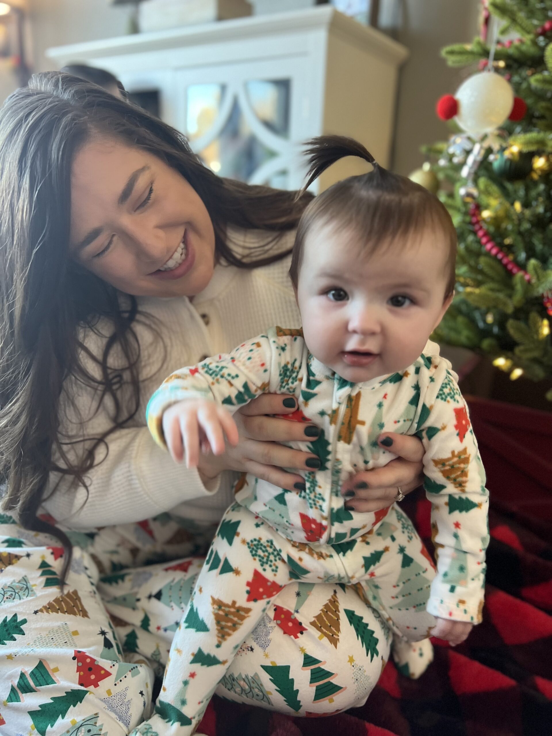 A photo of Kaitlin and a baby wearing holiday-themed pajamas.