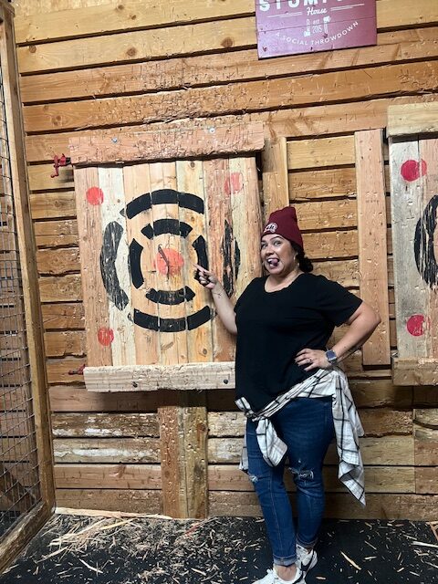 A photo of Melissa participating in axe throwing.