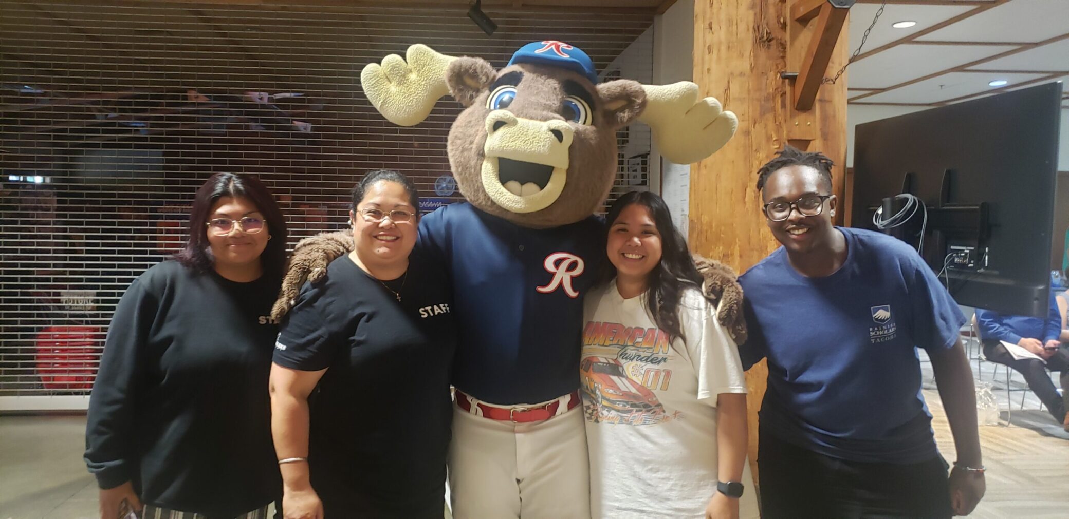 A photo of Sheryl and her summer team of people with Rhubarb, a moose mascot for a local sports team.