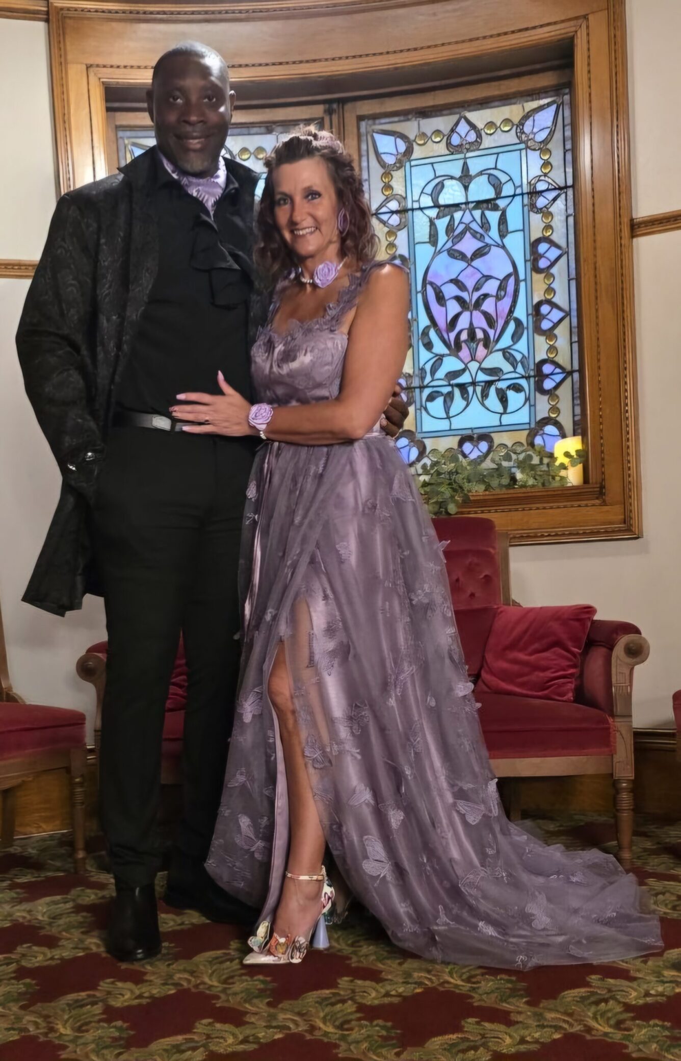 A photo of Rachel in a purple dress standing with her husband, Zeke.