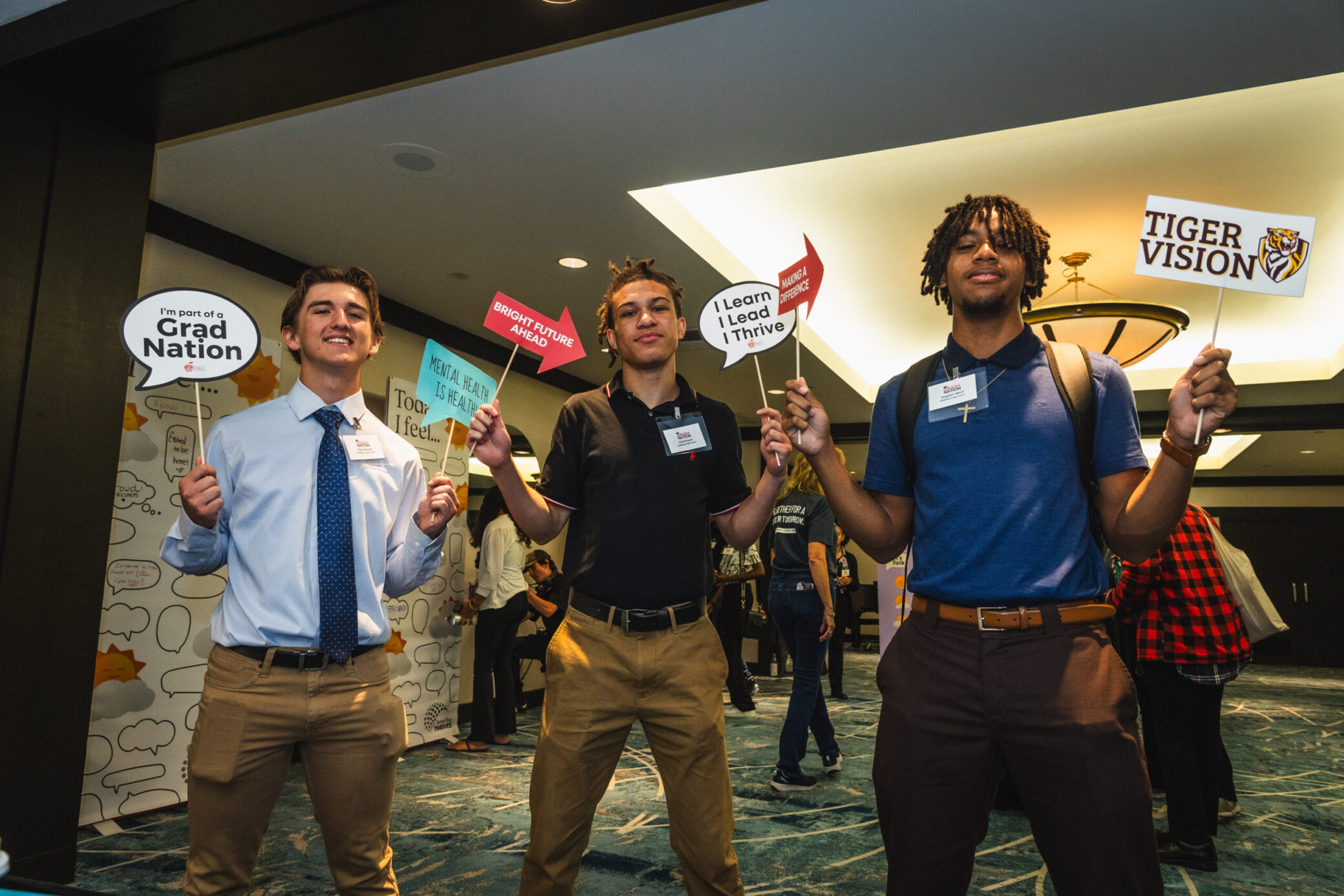 A photo of three young adults holding positive sayings on signs.