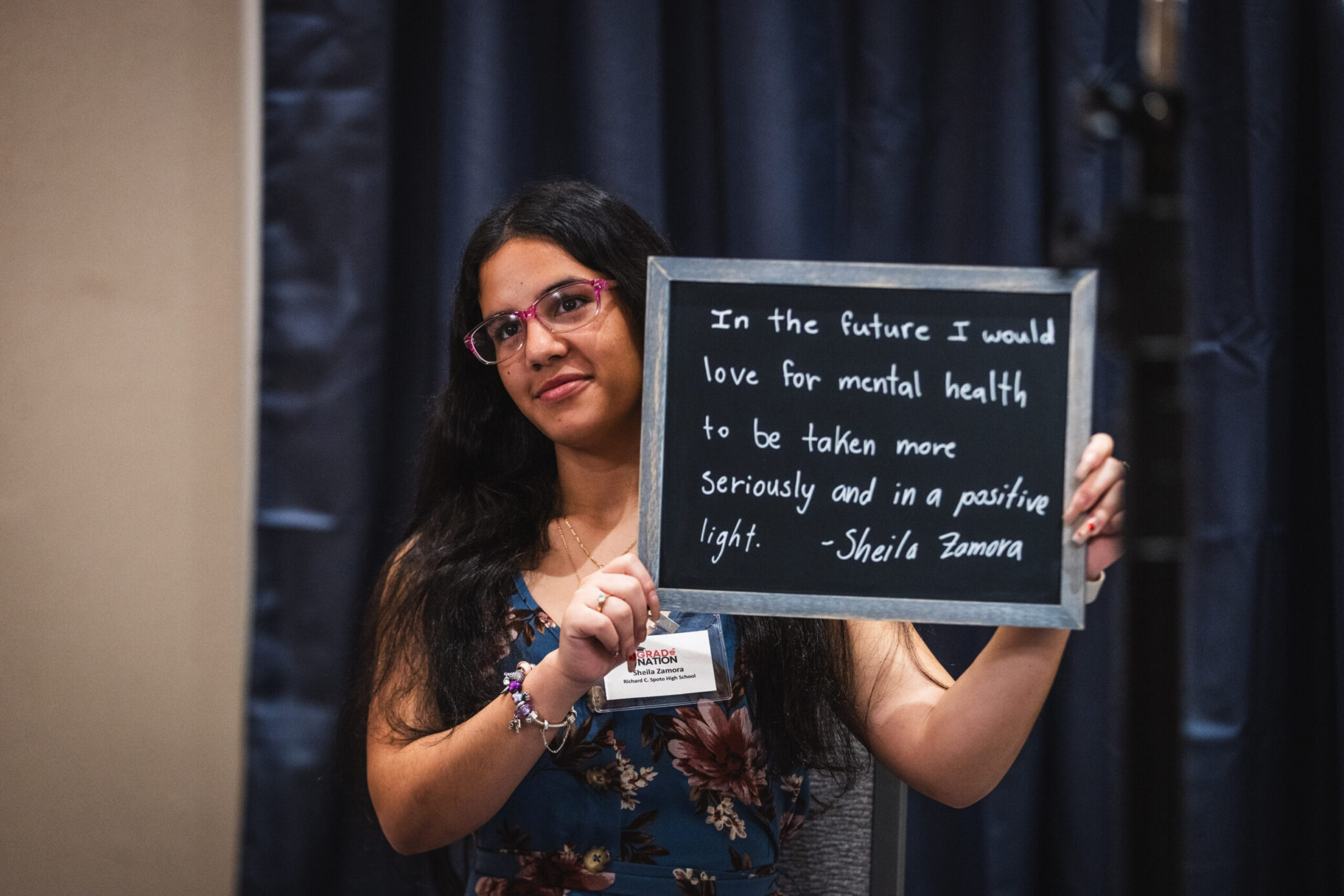 A photo of a woman holding a sign that shares about her dream for mental health to be taken seriously in the future.